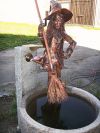 Origineller Brunnen mit Hexenskulptur, das Blatt ist der Wasserhahn, aus dem Besen fliest Wasser